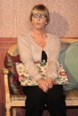 Grace Sims (Yvonne Doyle) sits, holding her work protectively.